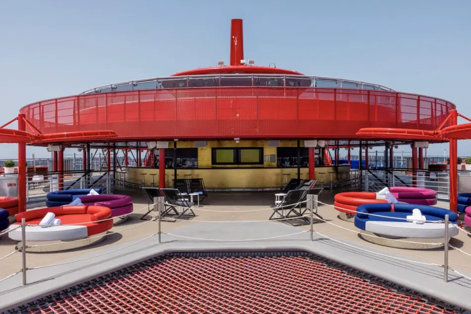 Red circular rooftop bar on a Virgin Voyages cruise ship with colorful lounge seating