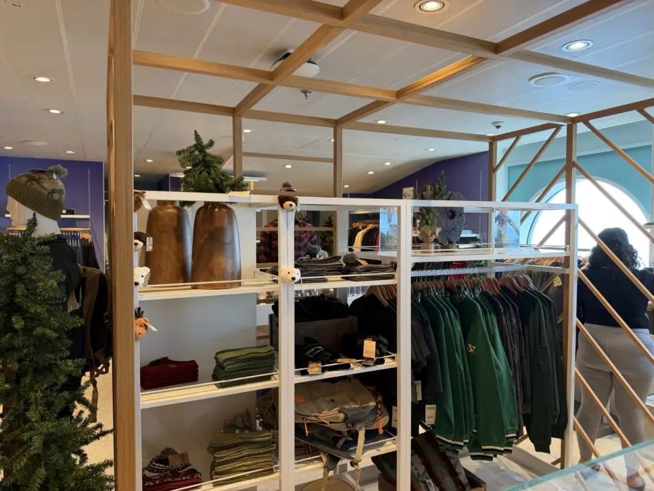 Bright clothing store interior with wooden framing, racks of jackets, and folded sweaters