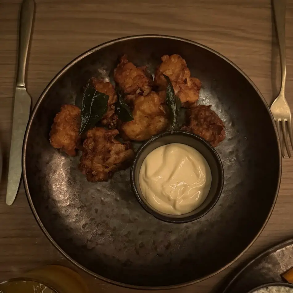 Crispy fried chicken bites with a creamy dip on a copper plate