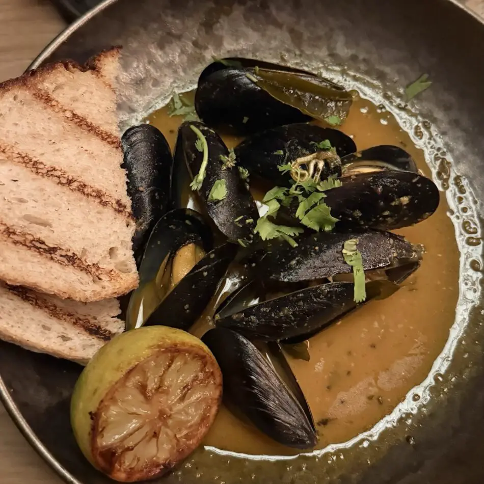 Mussels in sauce with crusty bread and a roasted potato
