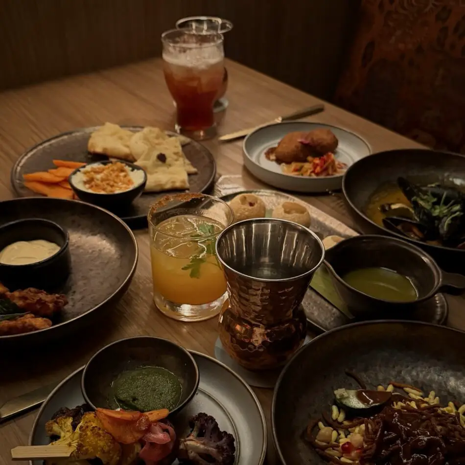 Assorted plated dishes and beverages on a wooden dining table