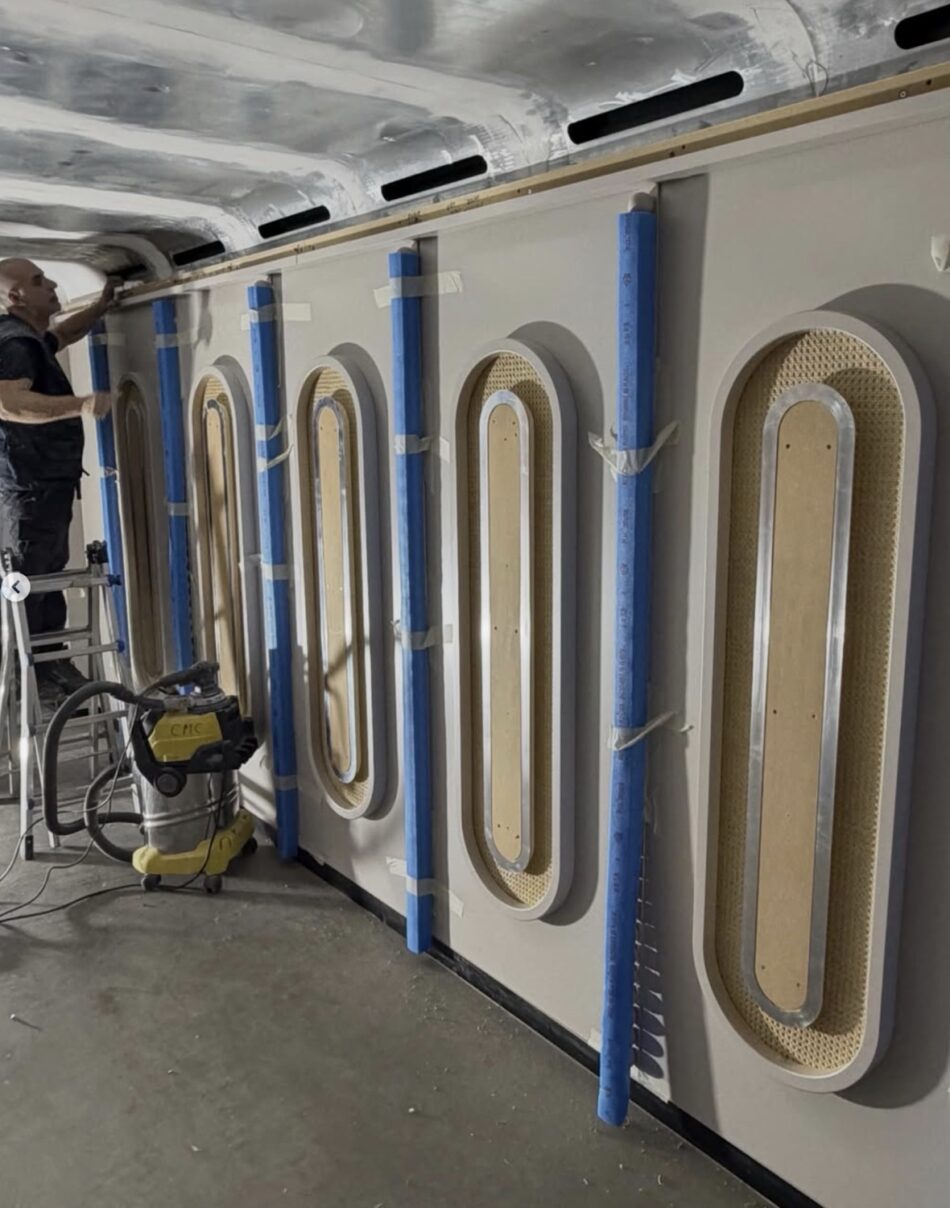 Worker installs wall panels inside a Virgin Voyages cabin under construction