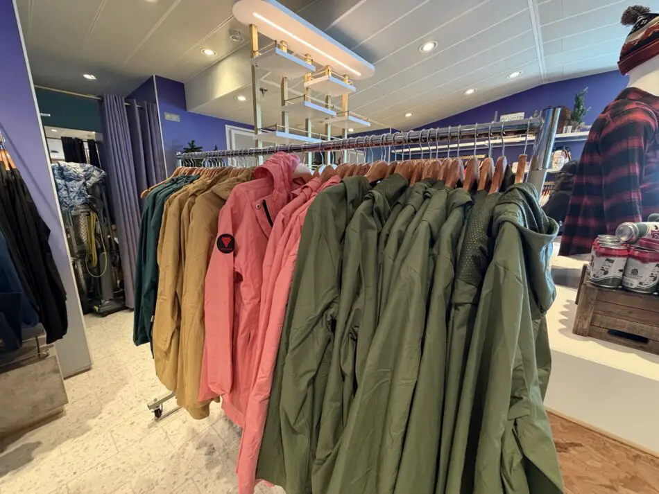 Rows of green, pink, and tan jackets on a clothing rack inside a shop