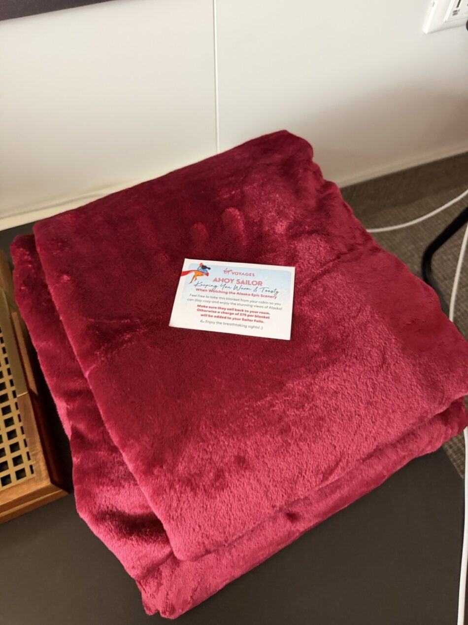 Folded red towel with Ahoy Sailor card on a Virgin Voyages cruise ship cabin