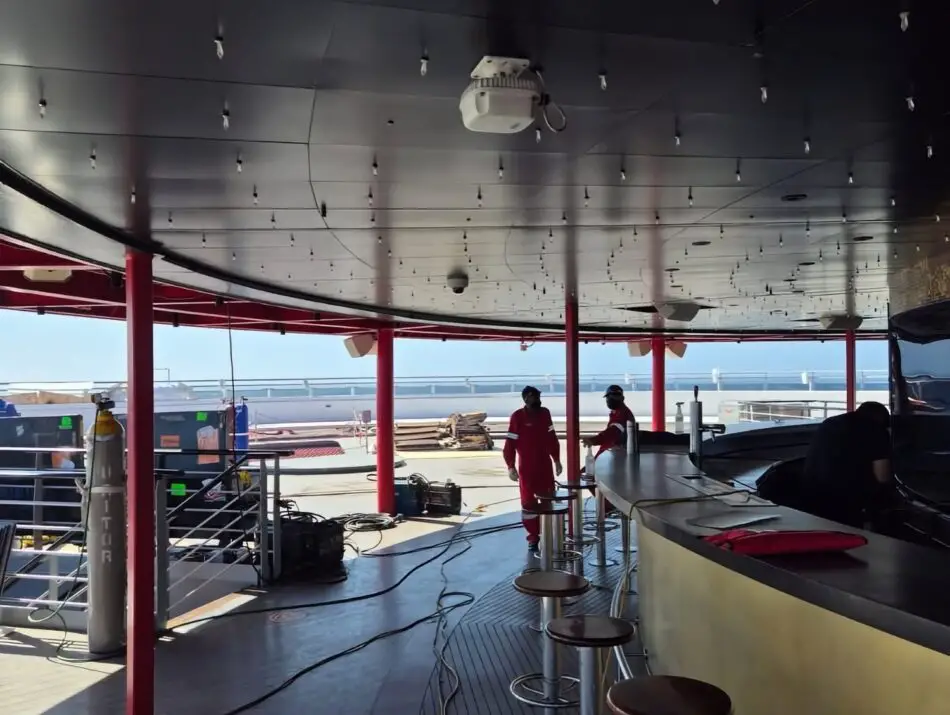 Outdoor bar area on a Virgin Voyages cruise ship with red pillars and stools