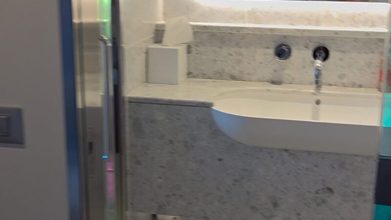 Cruise ship cabin bathroom with a marble sink, large mirror, and modern fixtures.