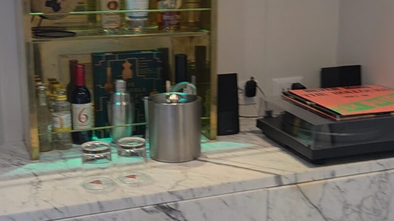 Virgin Voyages cruise ship cabin mini-bar with alcohol bottles, glasses, and a globe on a marble countertop.