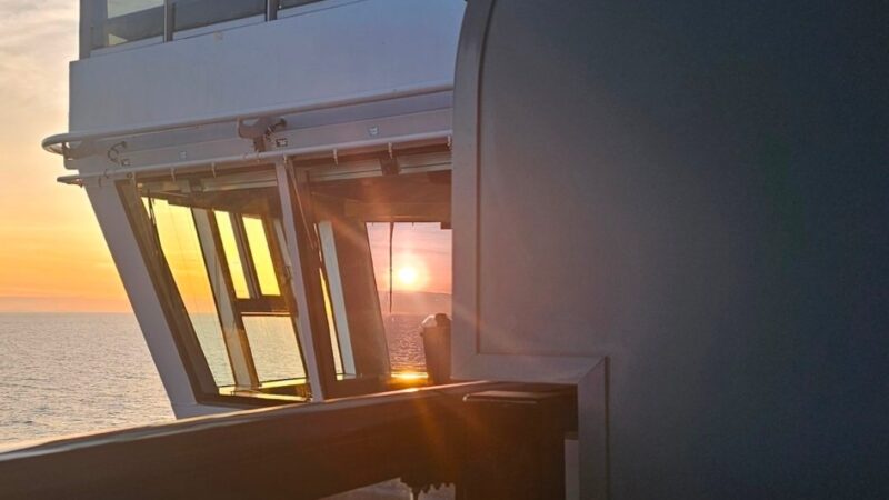 Sunset view from a Virgin Voyages cruise ship balcony, overlooking the ocean.