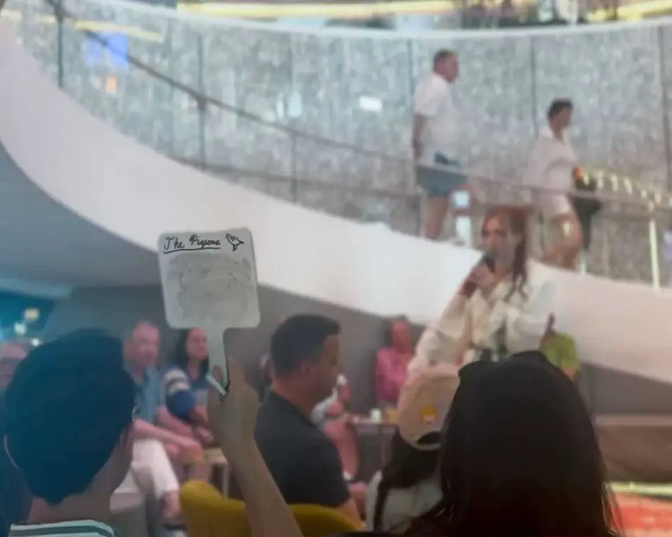 Audience watches a singer perform on a cruise ship atrium stage