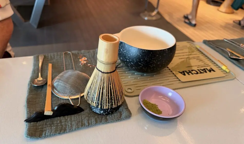 Bamboo matcha whisk, metal sieve, and bowl with powder on a table