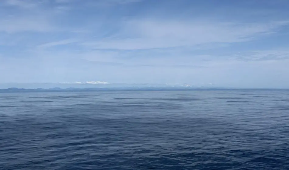 Calm blue ocean with distant land on the horizon and clear sky