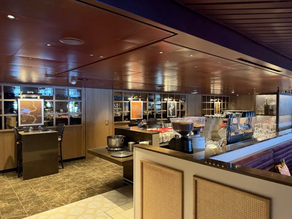 Cruise ship lounge bar with coffee station, seating, wood paneling, and framed art