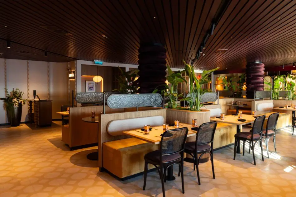Elegant cruise ship dining area with booths and plants on a Virgin Voyages ship