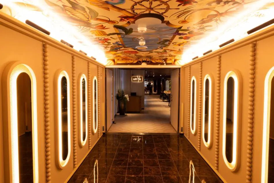 Corridor on a Virgin Voyages cruise ship with backlit oval mirrors and ornate ceiling