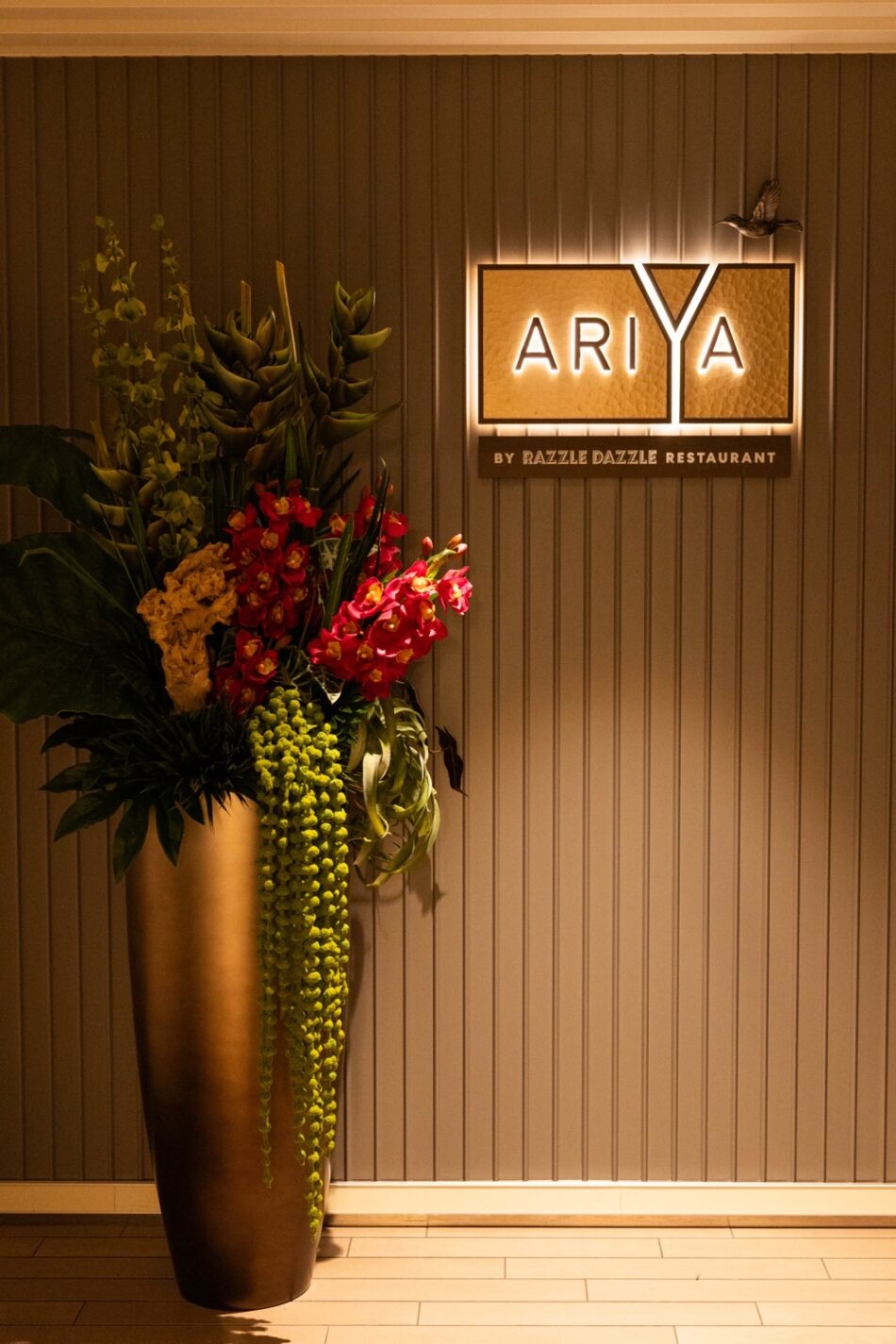 Ariya restaurant sign with a tall floral arrangement aboard Virgin Voyages