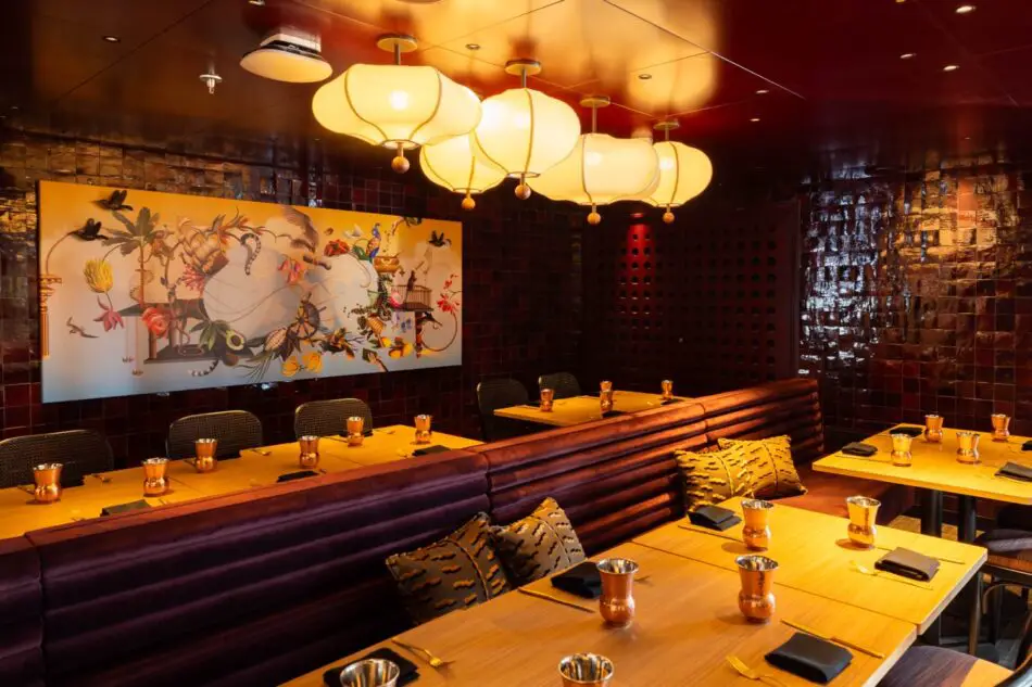 Elegant dining area with long wooden tables, copper cups, and warm lighting