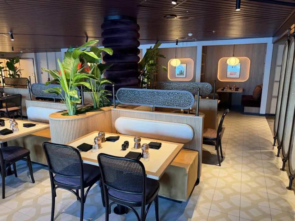 Dining area with booths and plants aboard a Virgin Voyages ship