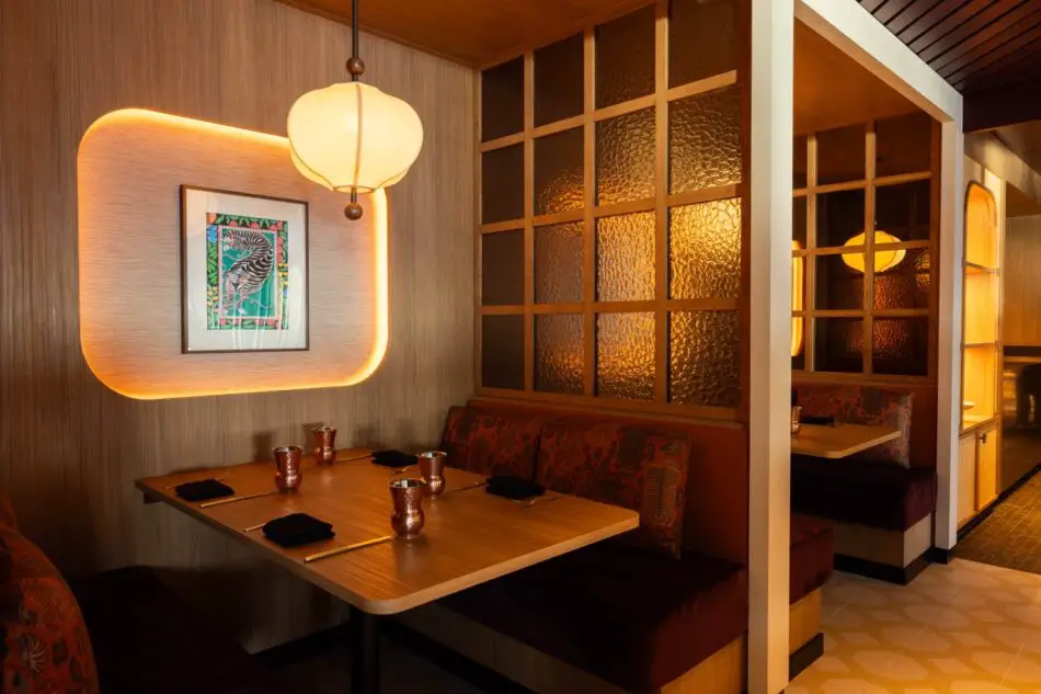 Warmly lit cabin dining area on a Virgin Voyages cruise ship with wood paneling
