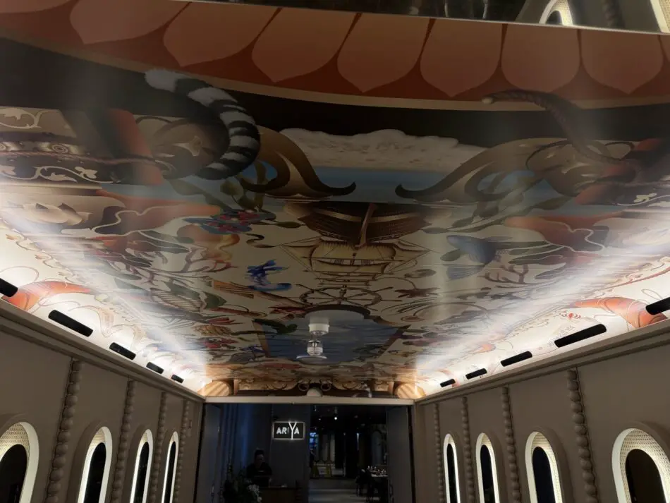 Long corridor on a Virgin Voyages cruise ship with a colorful ceiling mural