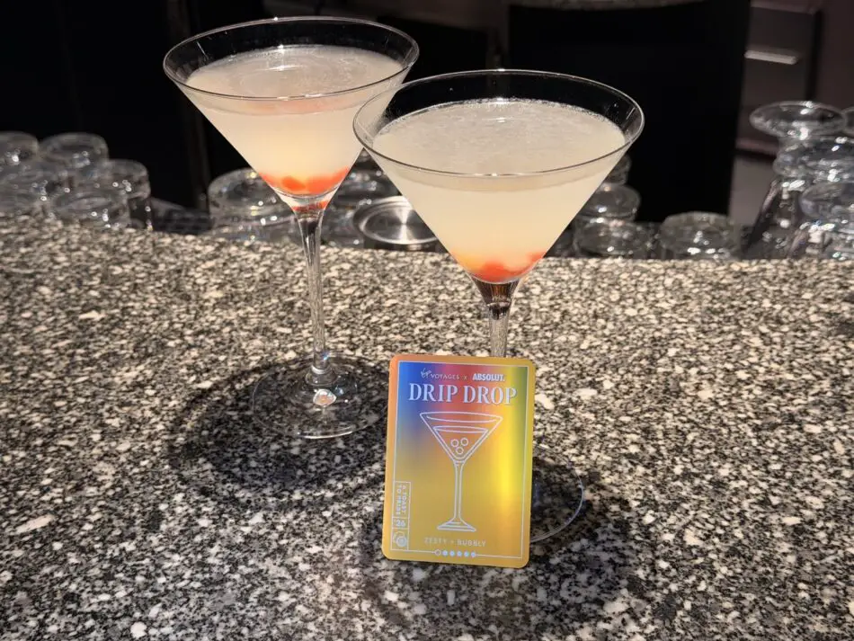 Two cocktails on a speckled bar with a DRIP DROP card aboard a Virgin Voyages ship