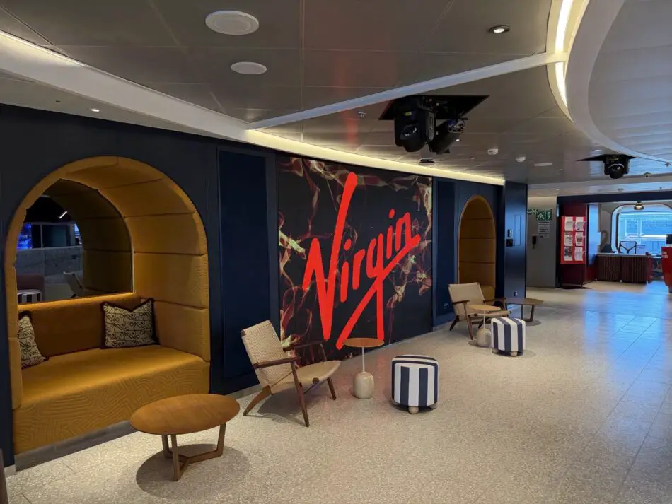 Virgin Voyages lounge on a cruise ship with mustard seating and large red logo wall