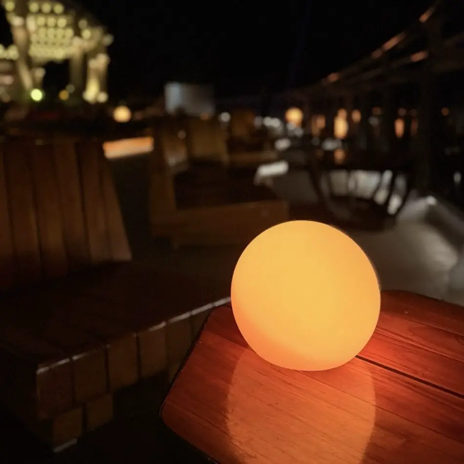 Glowing orange lamp on a wooden table on a Virgin Voyages cruise ship deck at night
