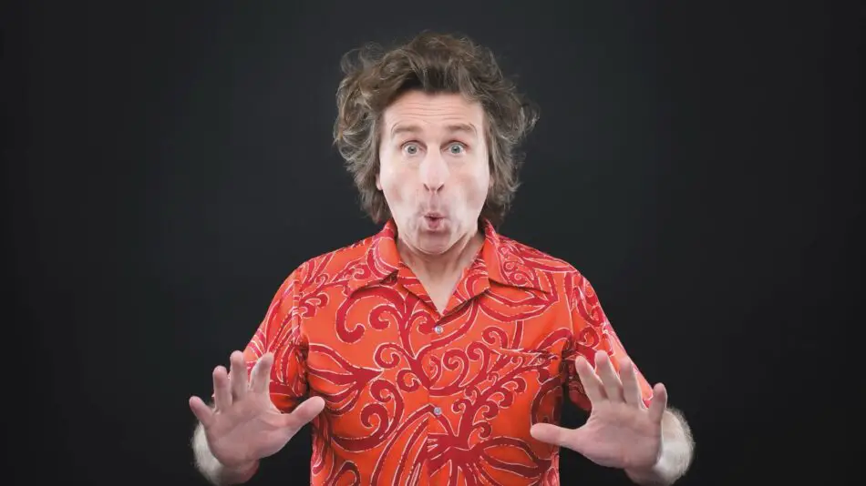 Man with a surprised expression wearing a red tropical shirt, hands raised