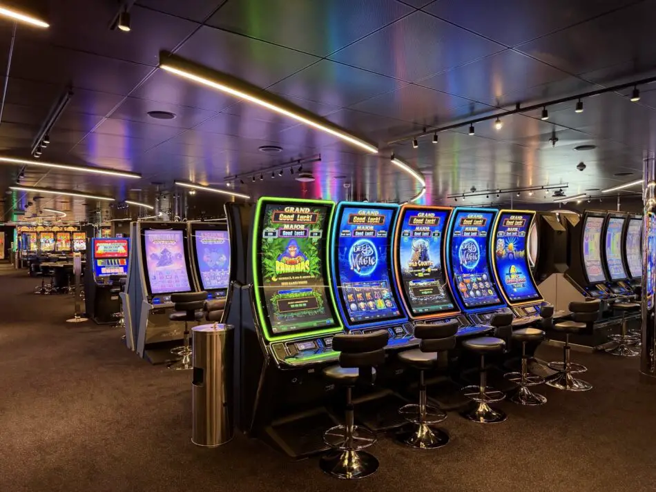 Row of glowing slot machines in a cruise ship casino on Virgin Voyages
