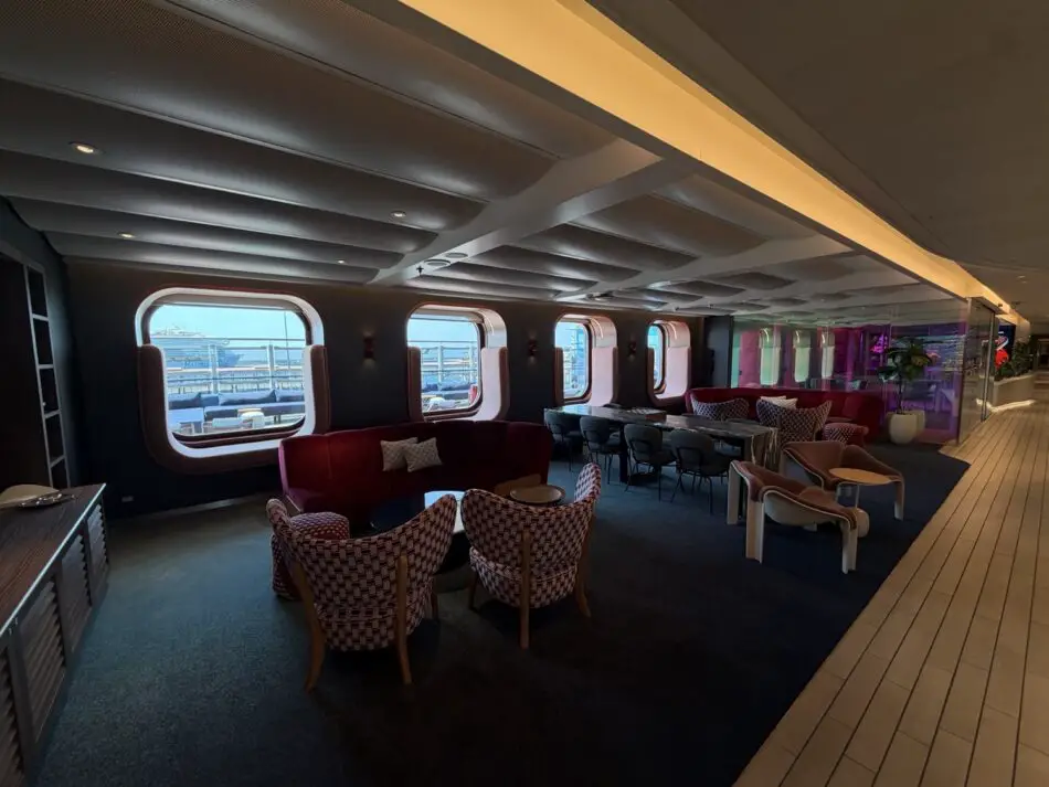 Elegant cruise ship lounge with curved windows and purple seating on a Virgin Voyages ship
