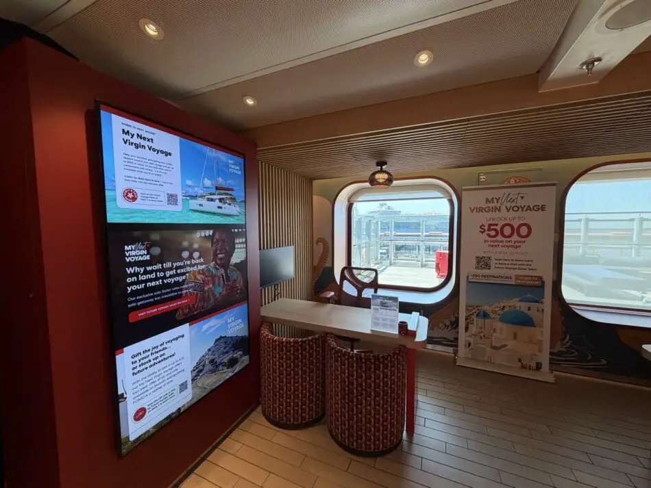 Virgin Voyages cruise ship cabin lounge with promotional displays and seating by the window