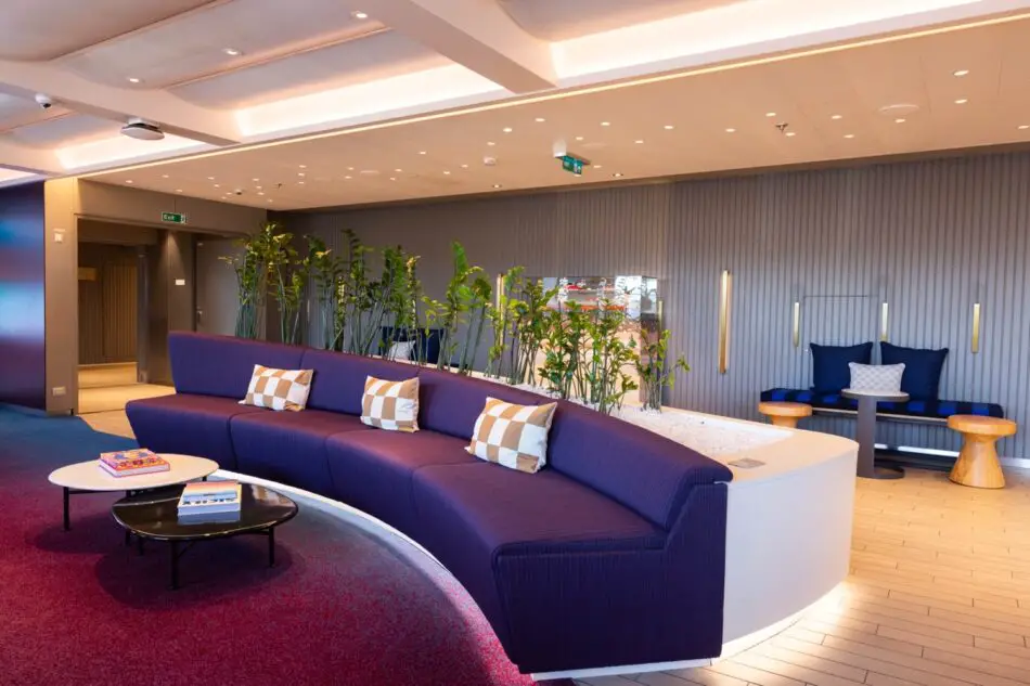 Virgin Voyages cruise ship lounge with a long purple curved sofa and plants