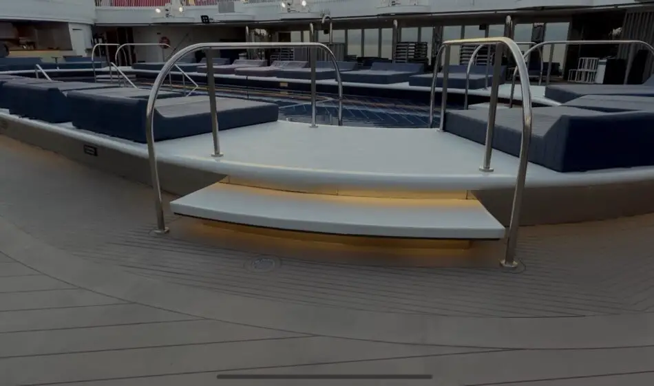 Pool deck lounge on a Virgin Voyages cruise ship with blue cushioned seating