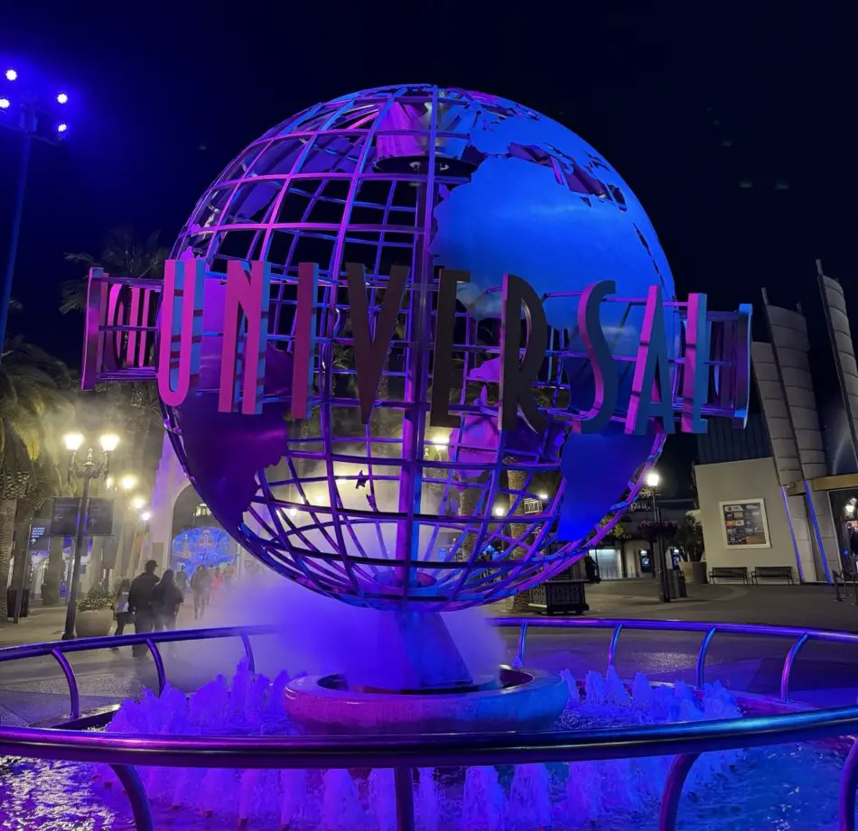 Illuminated globe sculpture with Virgin Voyages lettering at night near a fountain