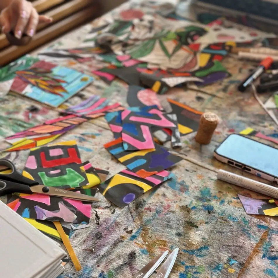 Colorful paper collage scraps scattered across a messy craft table