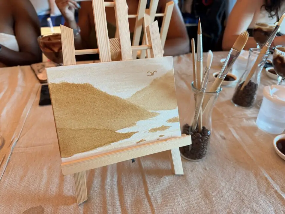 Small painting on an easel surrounded by brushes on a table