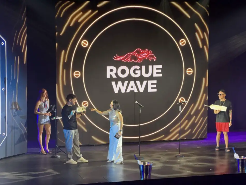People on stage with microphones in front of Rogue Wave logo backdrop