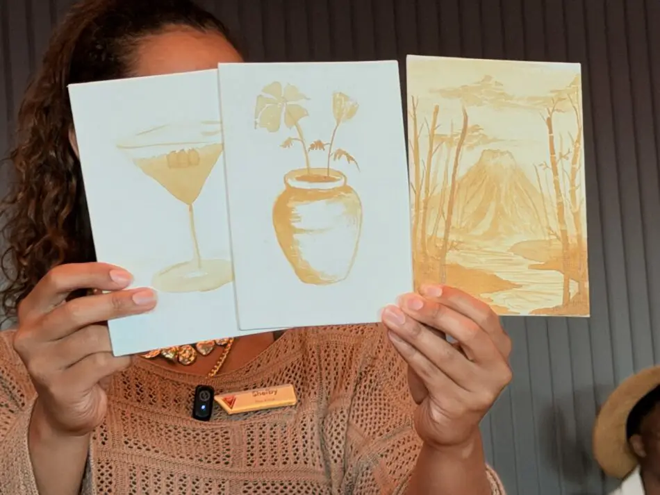 Three paintings of a martini glass, a vase, and a volcano on a Virgin Voyages cruise ship cabin