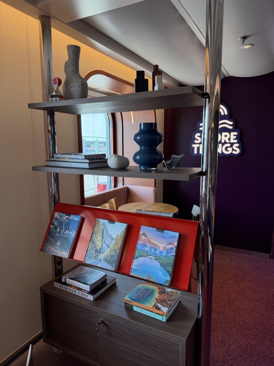 Interior of a Virgin Voyages cruise ship cabin with a shelving unit and magazines