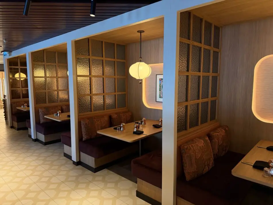 Wooden booth seating with frosted glass partitions in a warm, modern restaurant