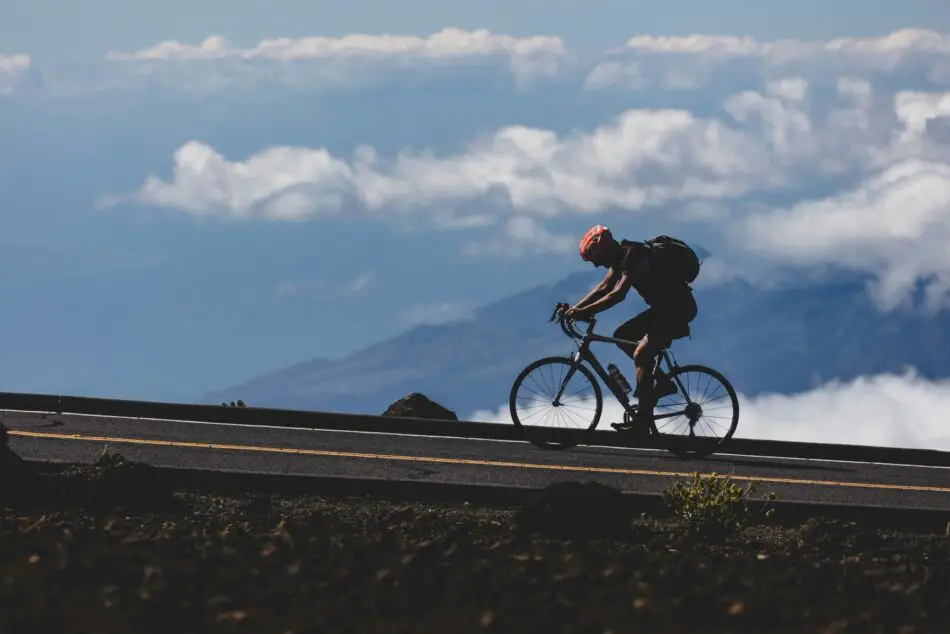 Cyclist wearing red helmet rides a road bike on a mountain road