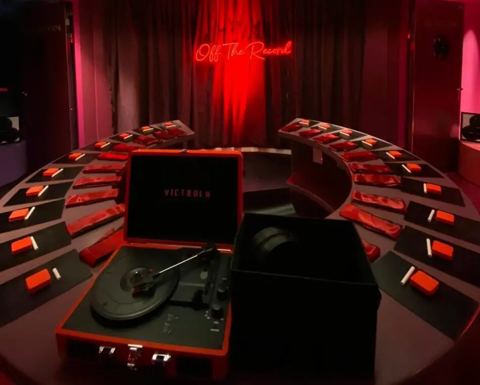 Red-lit circular studio with a vinyl turntable and neon Off The Record sign
