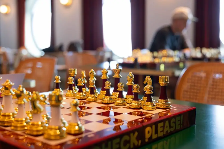 Gold chess pieces on a chessboard in a Virgin Voyages cruise ship lounge