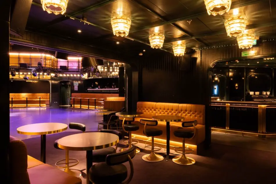 On a Virgin Voyages cruise ship lounge with round gold tables