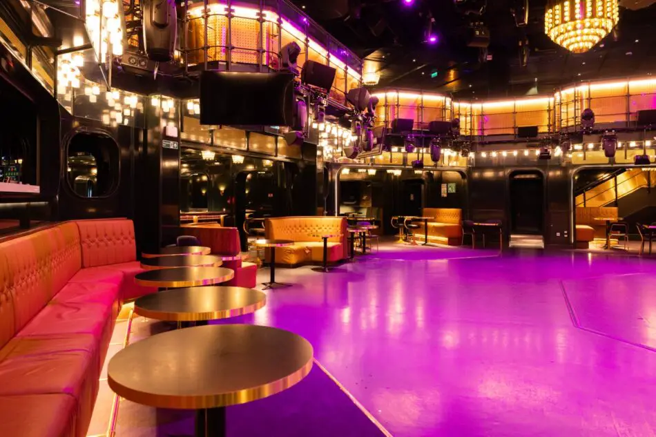 Lux lounge area with purple lighting aboard a Virgin Voyages cruise ship