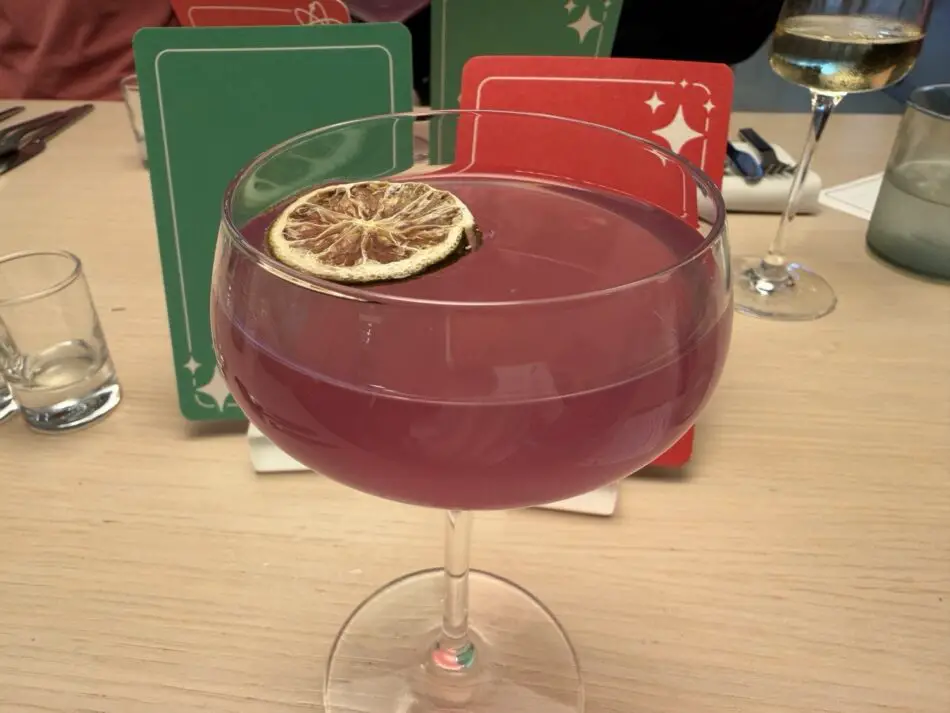 Pink cocktail with a dried lemon wheel garnish in a coupe glass