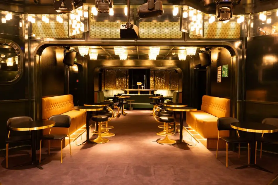 Luxurious ship lounge with warm lighting, orange banquettes and gold accents