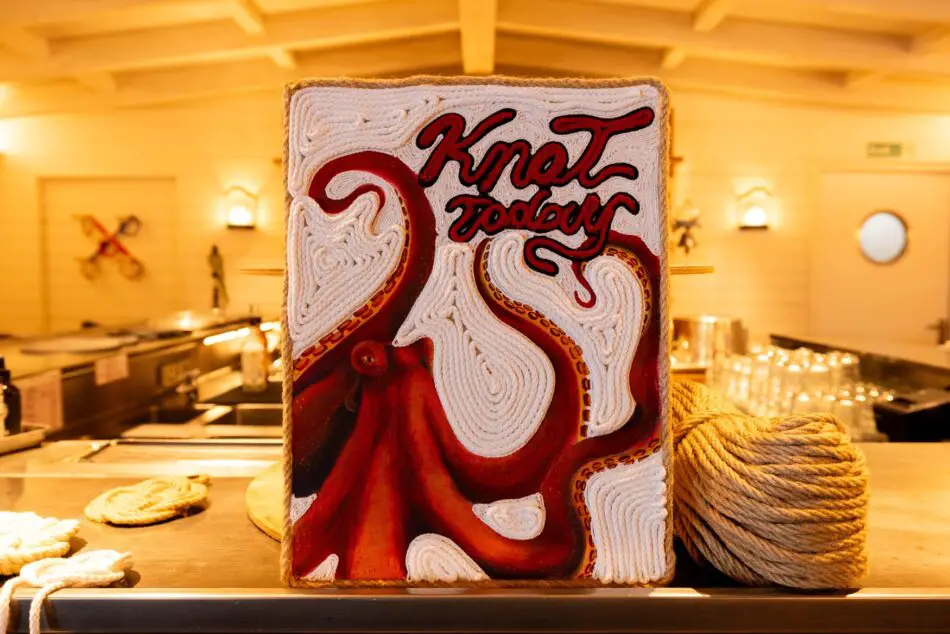 Rope art sculpture with Knot Today text on a wooden block in a warmly lit bar