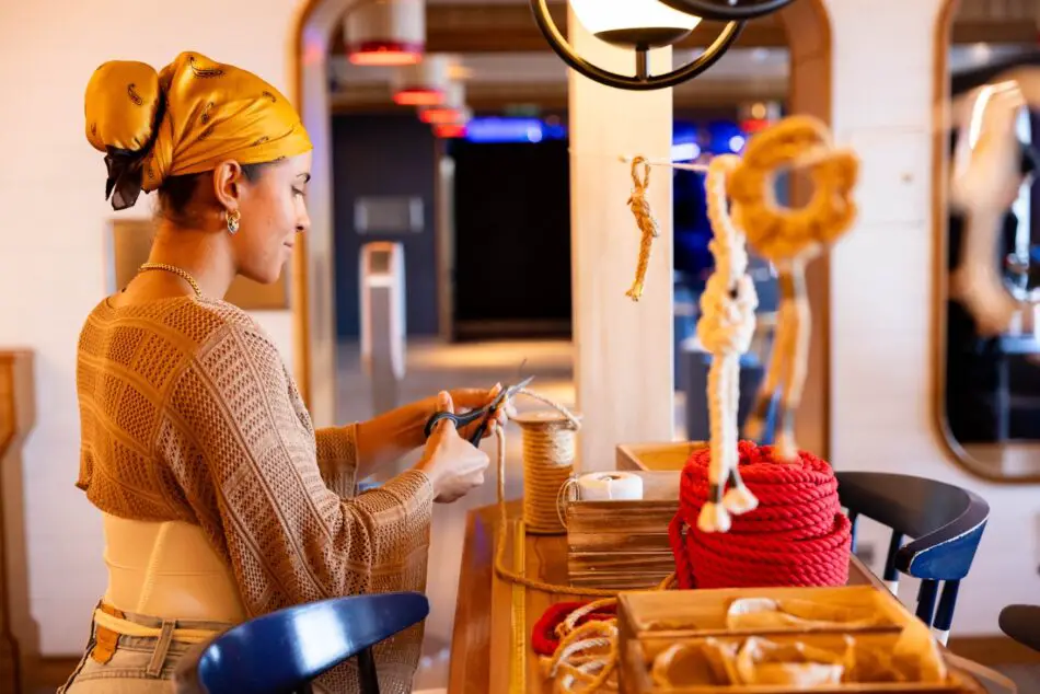 Woman cutting rope at a shipboard craft area on a Virgin Voyages cruise ship