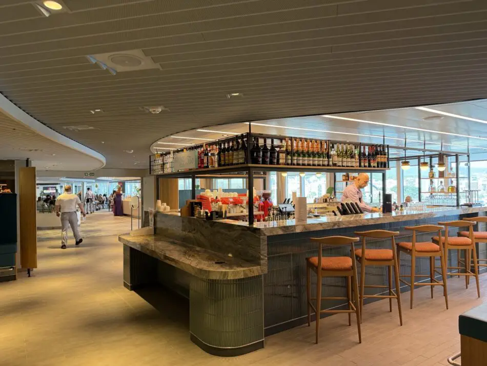 Bar on a cruise ship with marble counter, bartender, and bottles