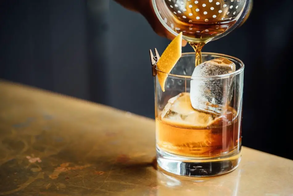 Whiskey poured over ice in a rocks glass with citrus garnish